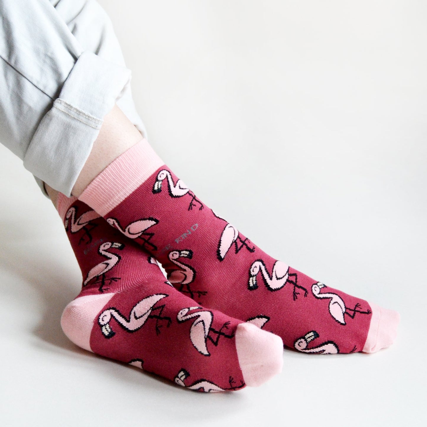 model sitting with ankles crossed wearing hot pink flamingo socks