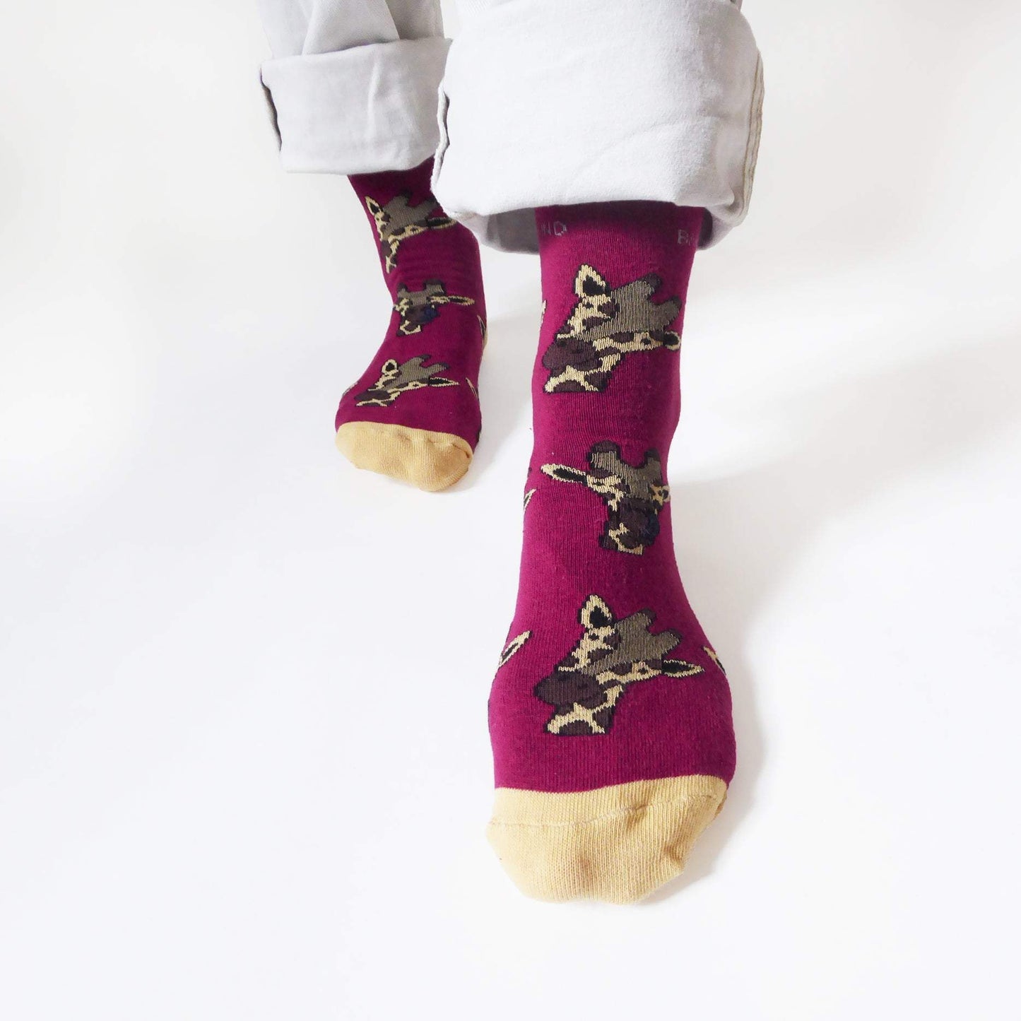 closeup of standing model wearing bamboo giraffe socks. the left foot is forward, highlight the burgundy bamboo sock