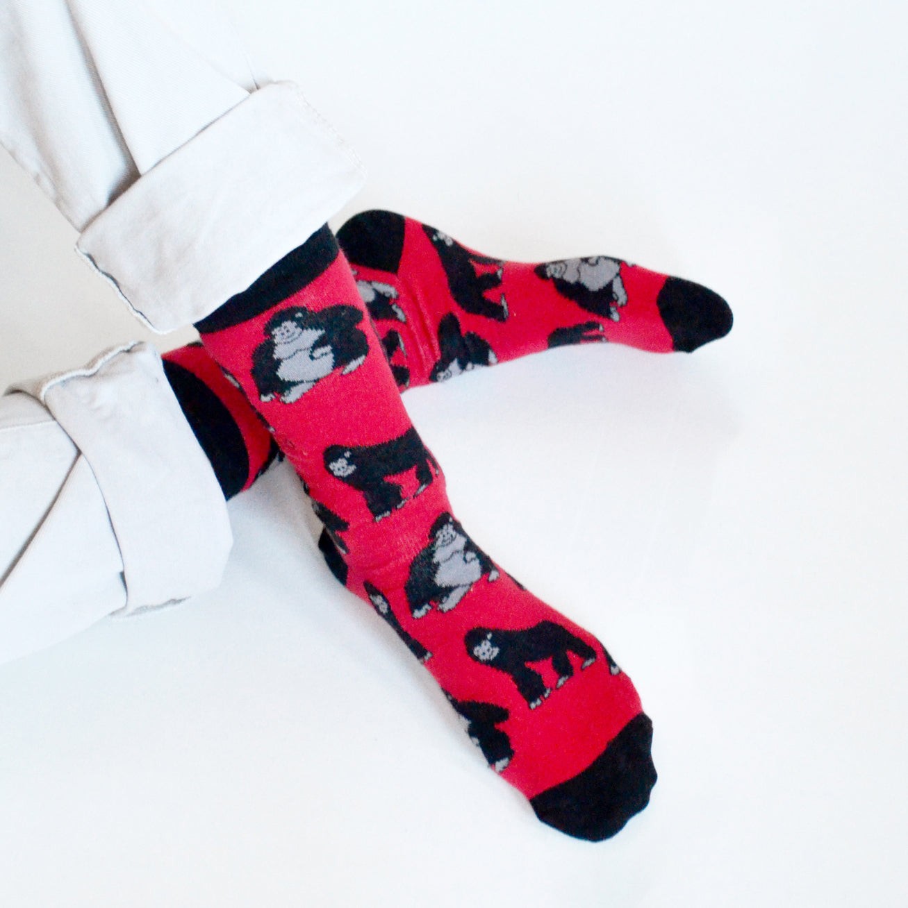 sitting model with ankles crossed wearing red and black bamboo socks with gorilla design woven into it