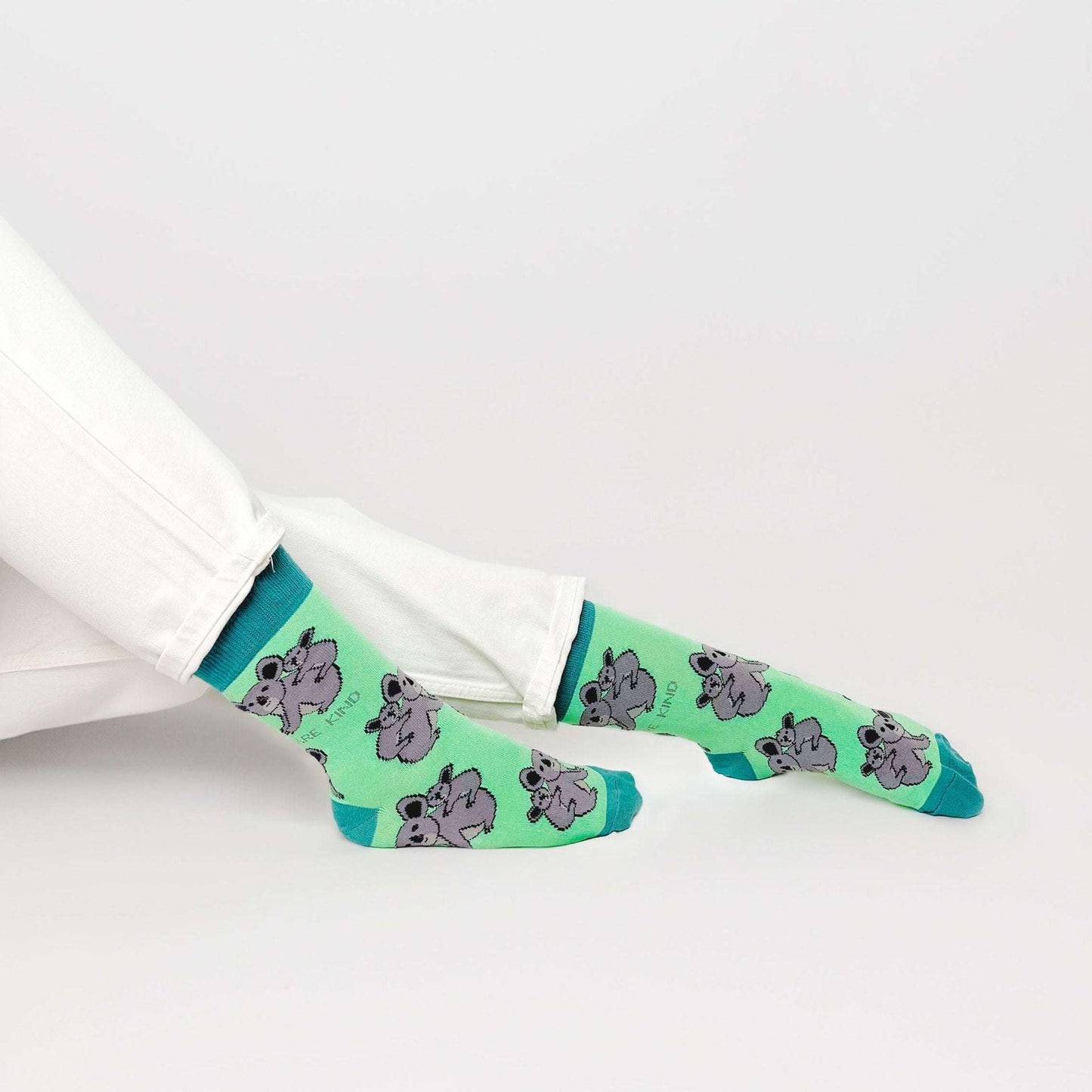 sitting model with feet outstretched wearing green koala socks