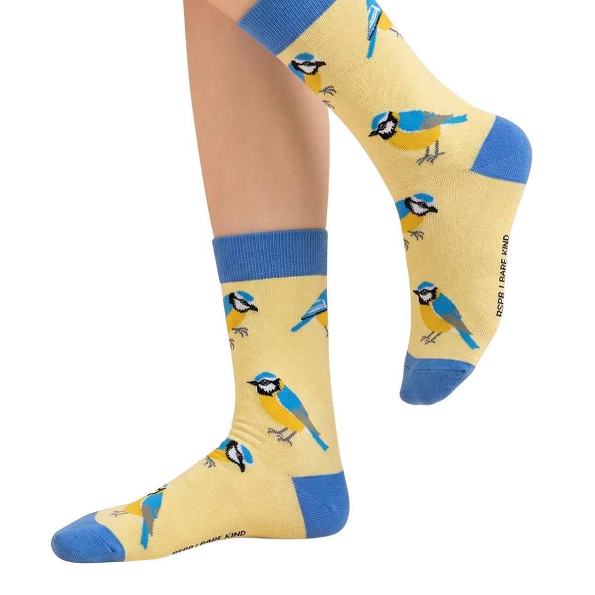 A pair of crew socks worn on a person's feet, featuring a repeating pattern of blue tits on a pale yellow background with blue ribbed cuffs and blue toes and heels.
