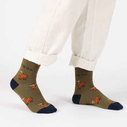 model with white trousers wearing green highland cow bamboo socks