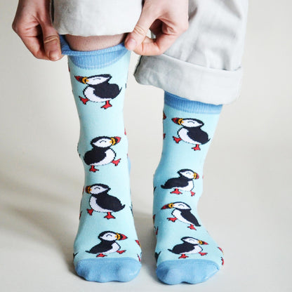 Light blue socks with puffin design worn by a person on a plain background