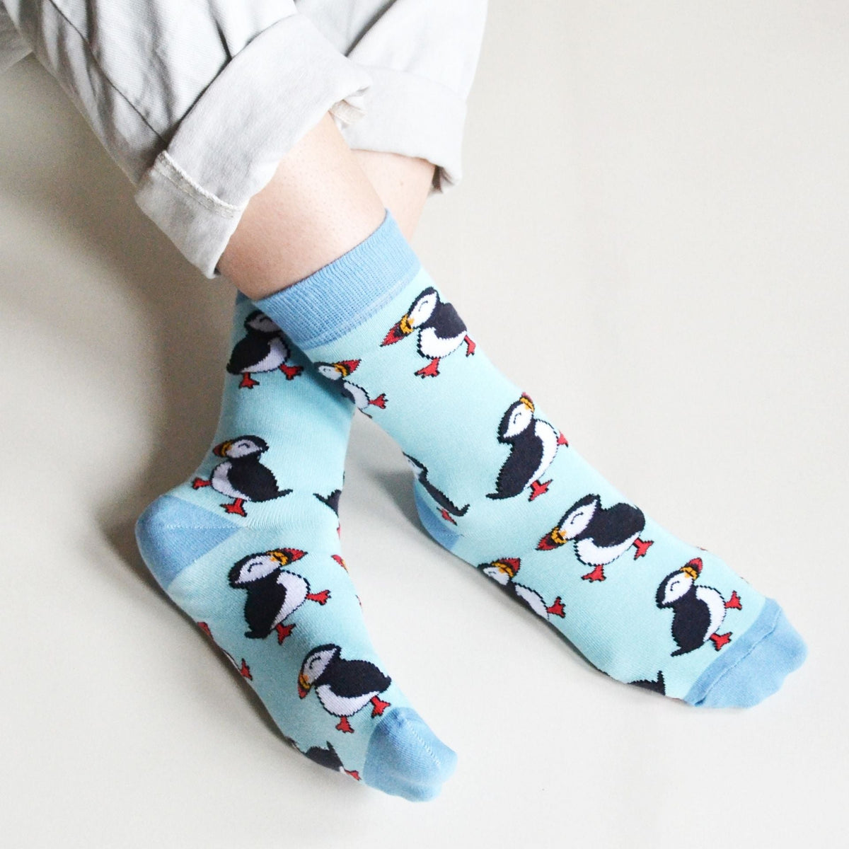 Light blue socks with puffin pattern worn by a person on a light background