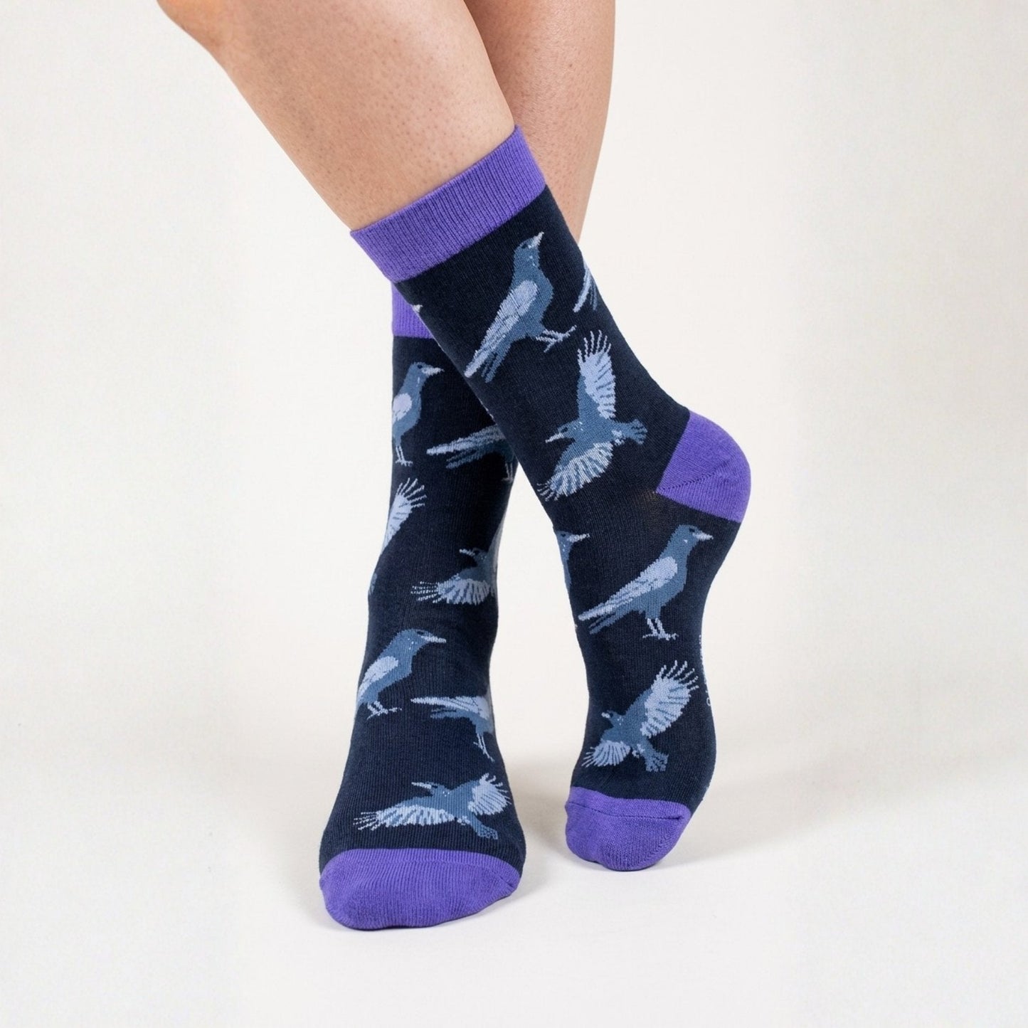 Black socks with blue raven patterns and purple accents on a white background