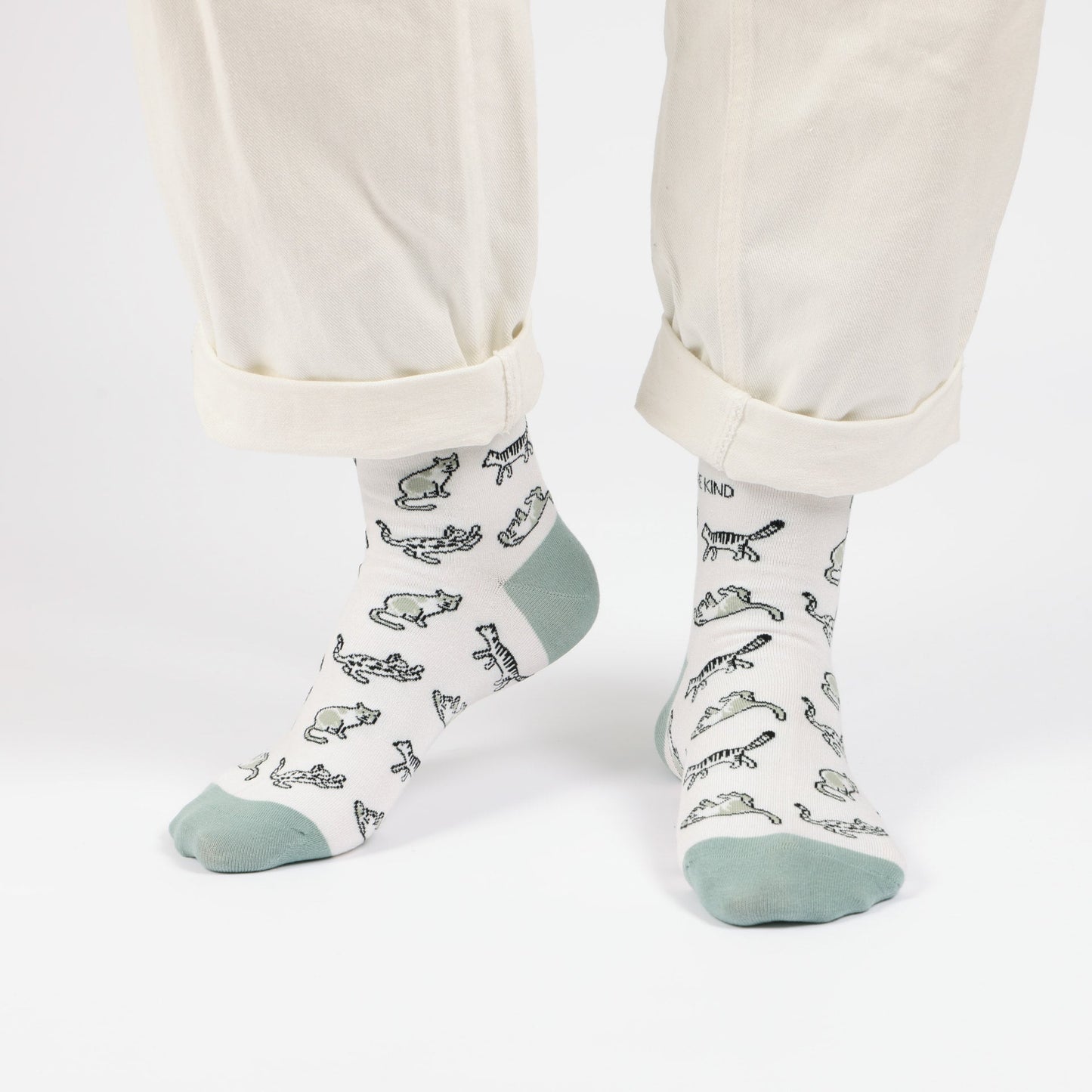 model with white trousers wearing green cat bamboo socks